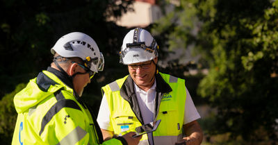 Kaksi Oulun Energian Sähköverkko Oy:n työntekijää juttelevat keskenään ulkona. 