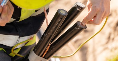 An employee of Oulun Energia is holding black electrical wires.
