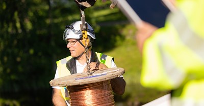 Oulun Energian työntekijä ohjaa minne kuparistakaapelia lasketaan.
