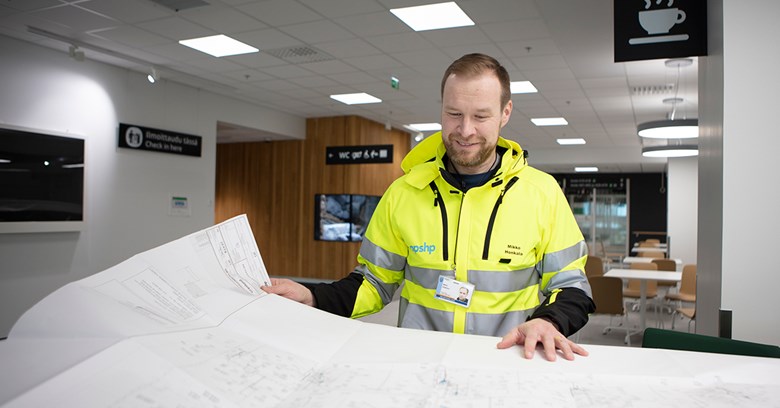 Mikko Honkala levittää pöydälle ison kartan ja hymyilee.