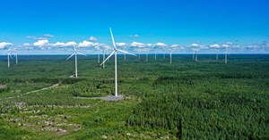 Ilmakuvassa näkyy tuulivoimaloita suomalaisessa metsämaisemassa. 