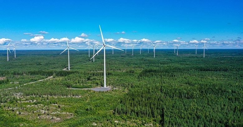 Ilmakuvassa näkyy tuulivoimaloita suomalaisessa metsämaisemassa. 