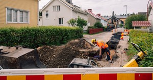 Urakoitsija työskentelee kaukolämpötyömaalla, joka sijaitsee omakotitaloalueella. 